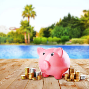 Salvadanaio rosa con monete vicino alla piscina