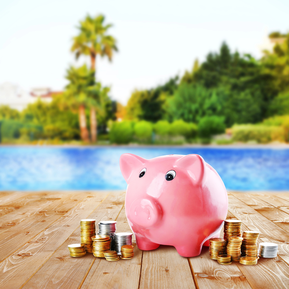 Salvadanaio rosa con monete vicino alla piscina